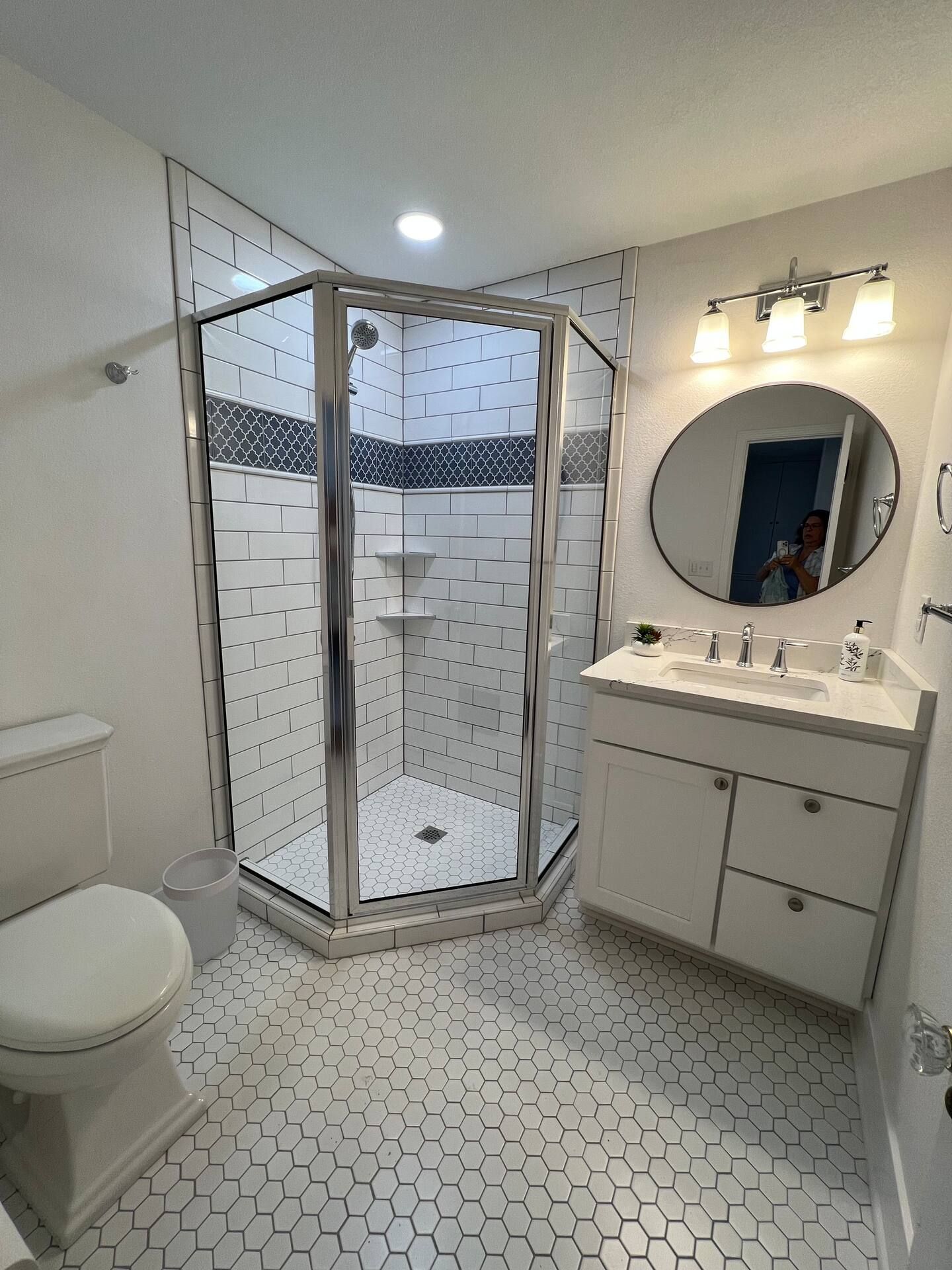 A bathroom with a toilet , sink , shower and mirror.