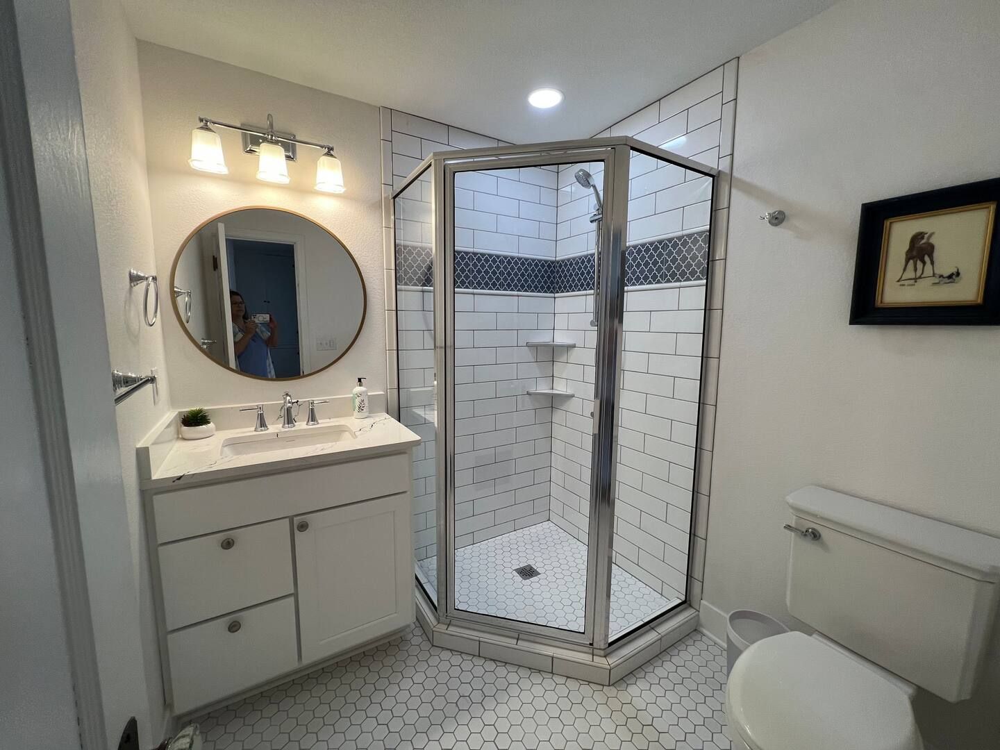 A bathroom with a shower , sink , toilet and mirror.