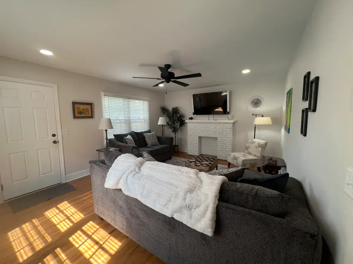A living room with a couch , chairs , television and fireplace.