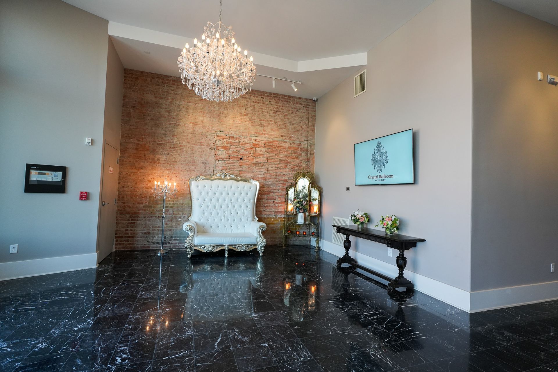 Entryway with a white chair and a chandelier.