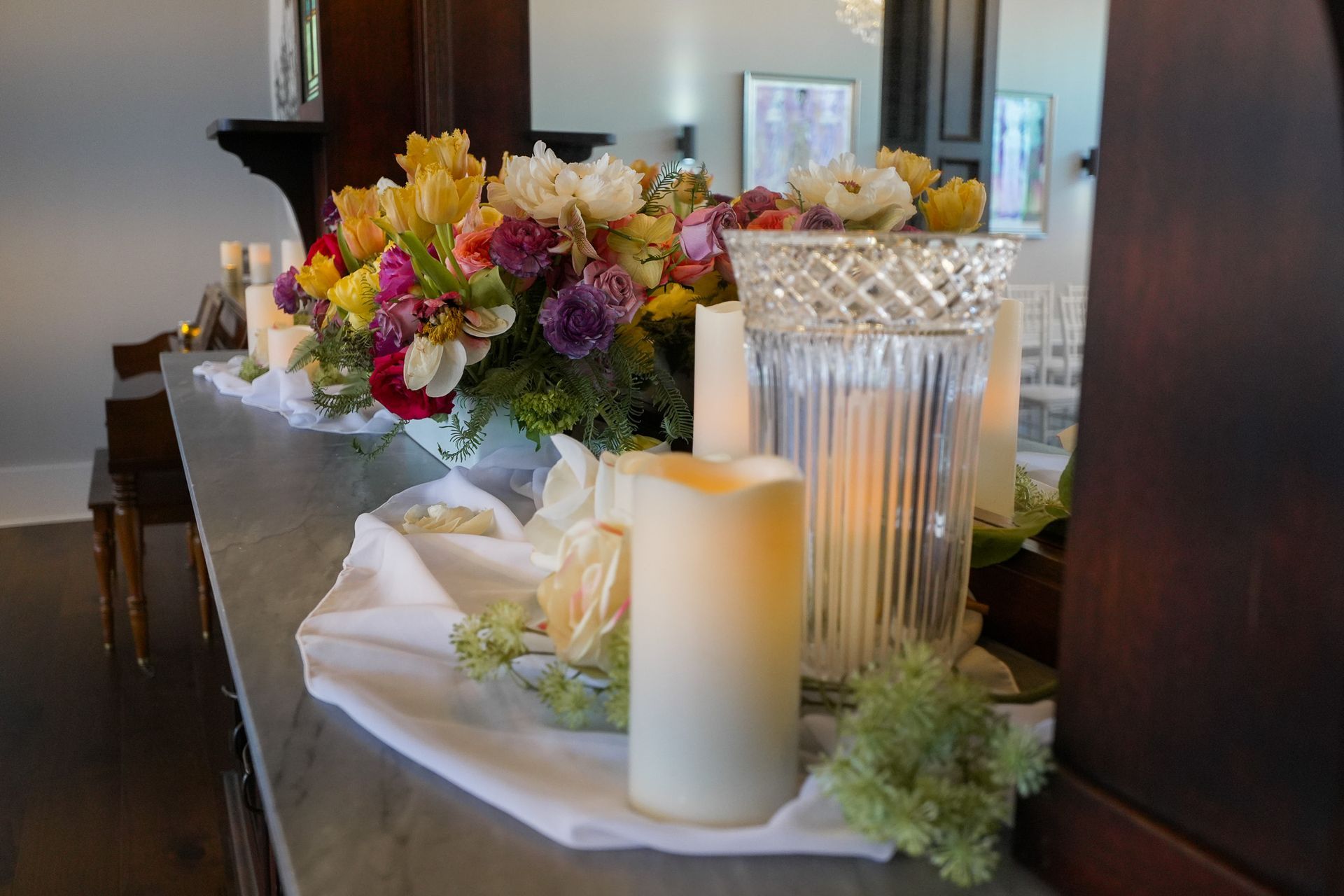 A table with a vase of flowers and candles on it.