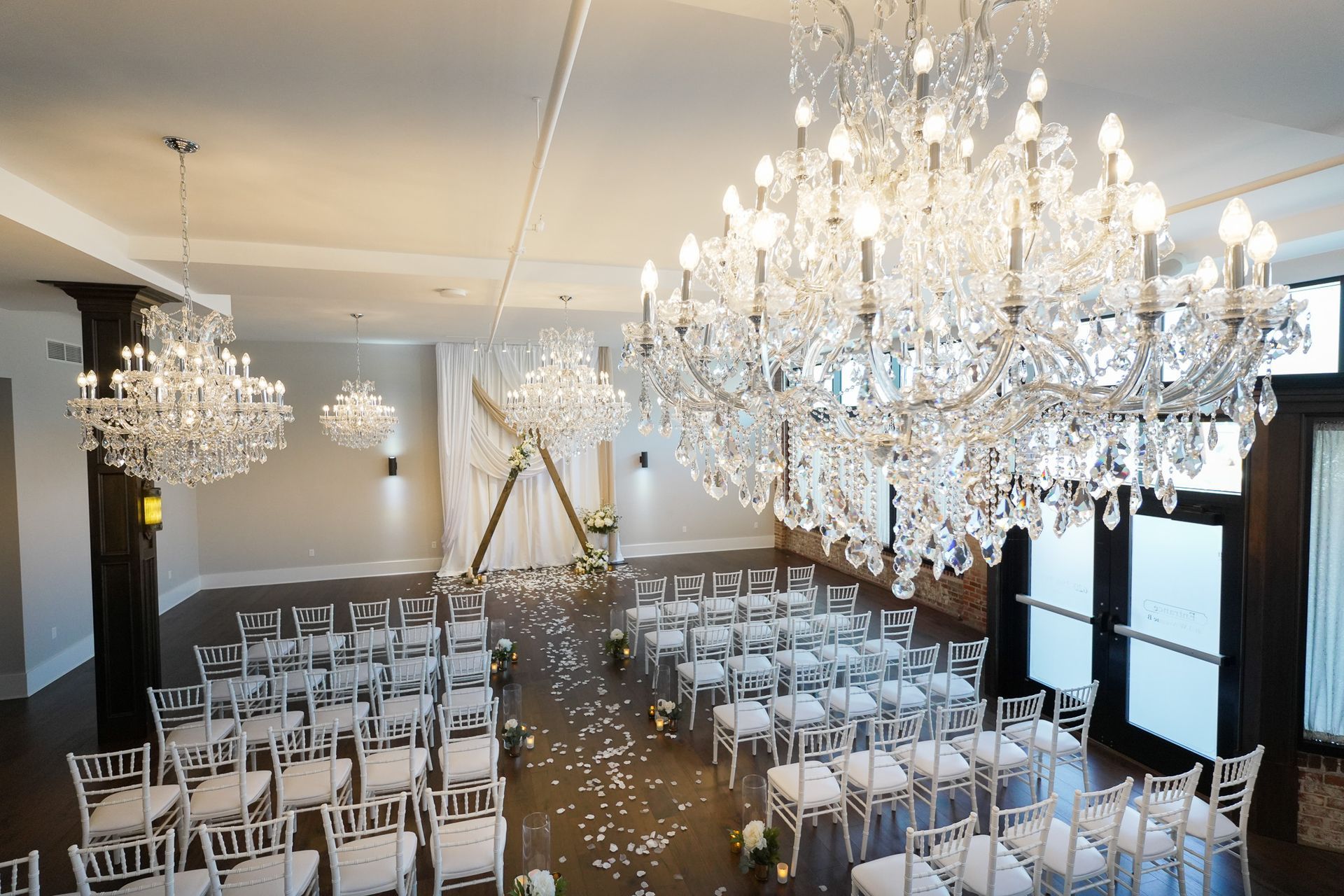 A large room filled with chairs and chandeliers for a wedding ceremony.
