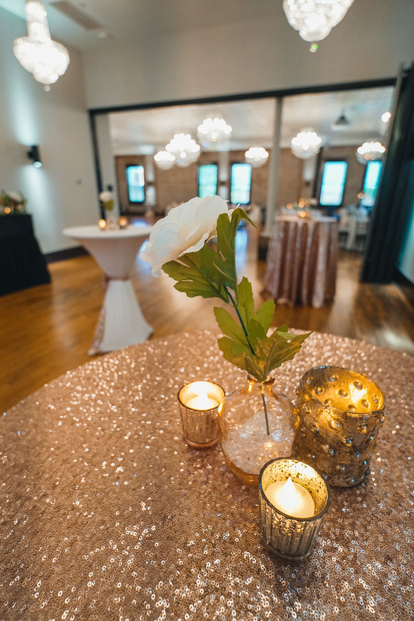A table with candles and flowers on it in a large room.