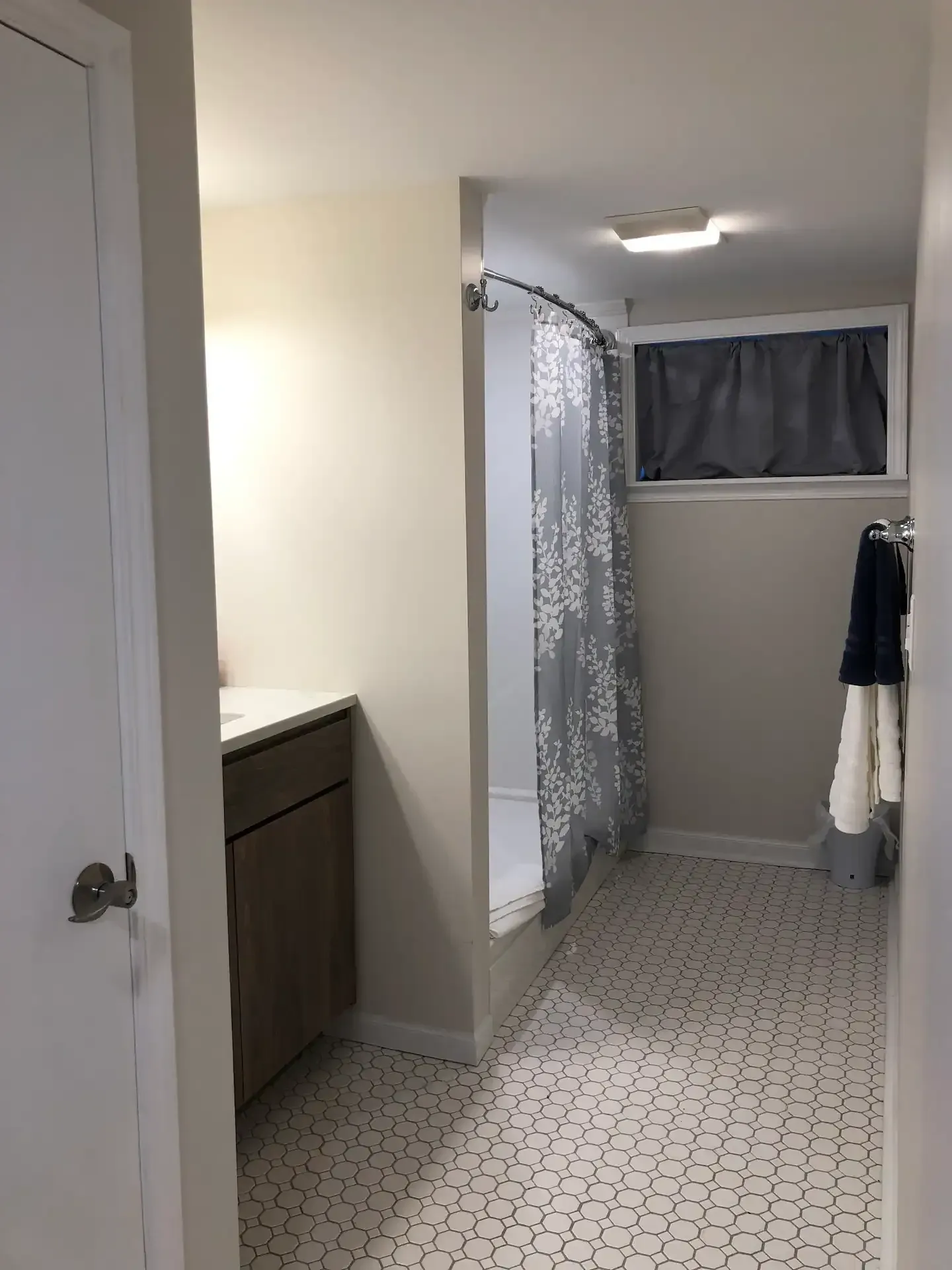 A bathroom with a shower , sink , and window.