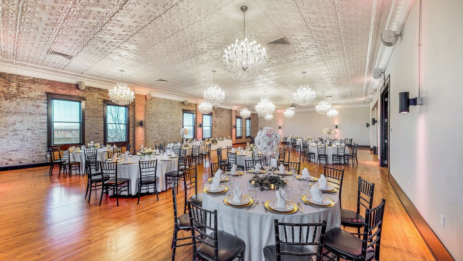 A large room with tables and chairs set up for a wedding reception.