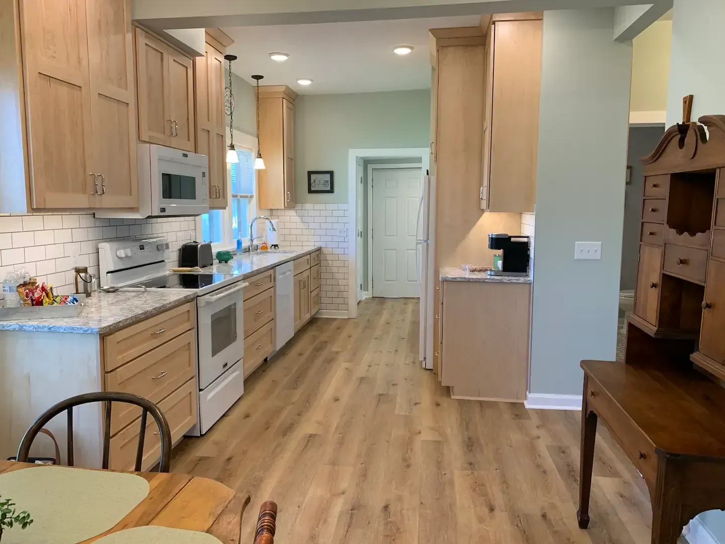 A kitchen with wooden cabinets , a table and chairs.