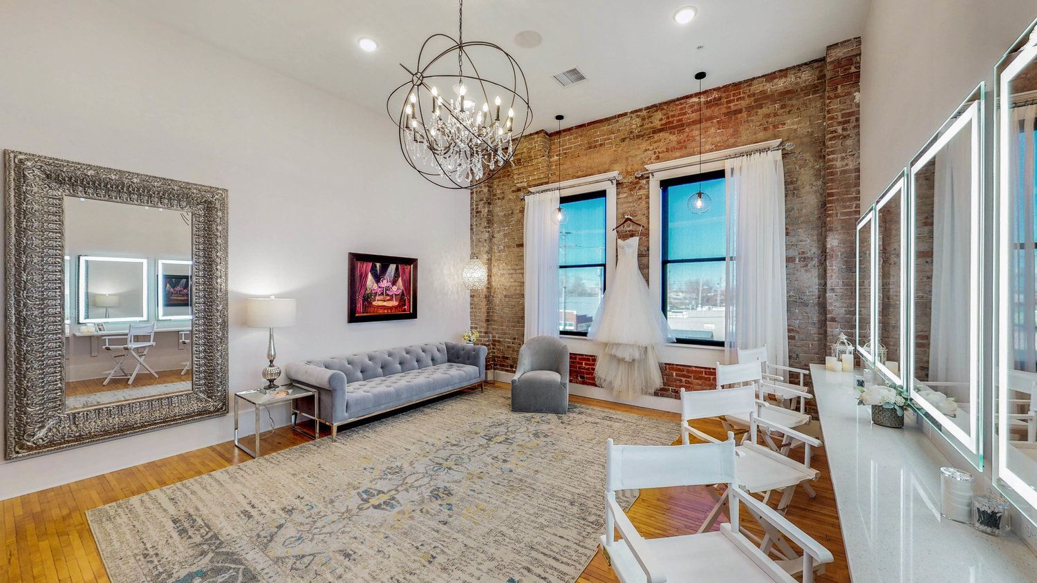 A room with a couch , chairs , mirrors and a chandelier.