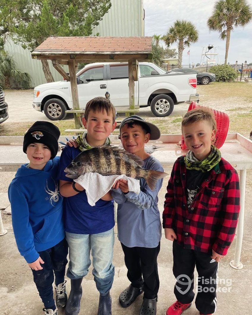 A group of young boys are standing next to each other holding a large fish.