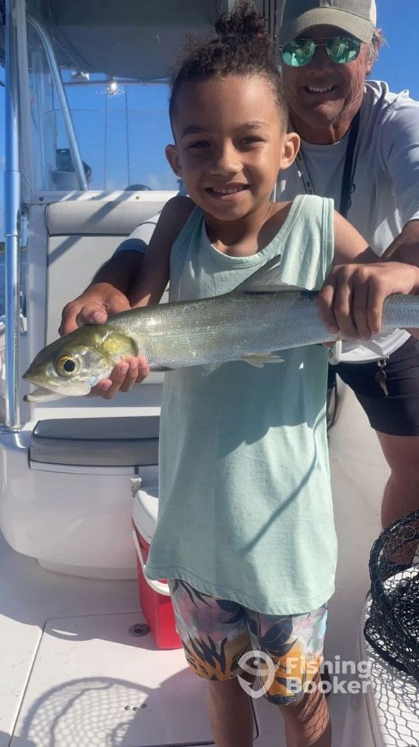 A man and a little boy are holding a fish on a boat.