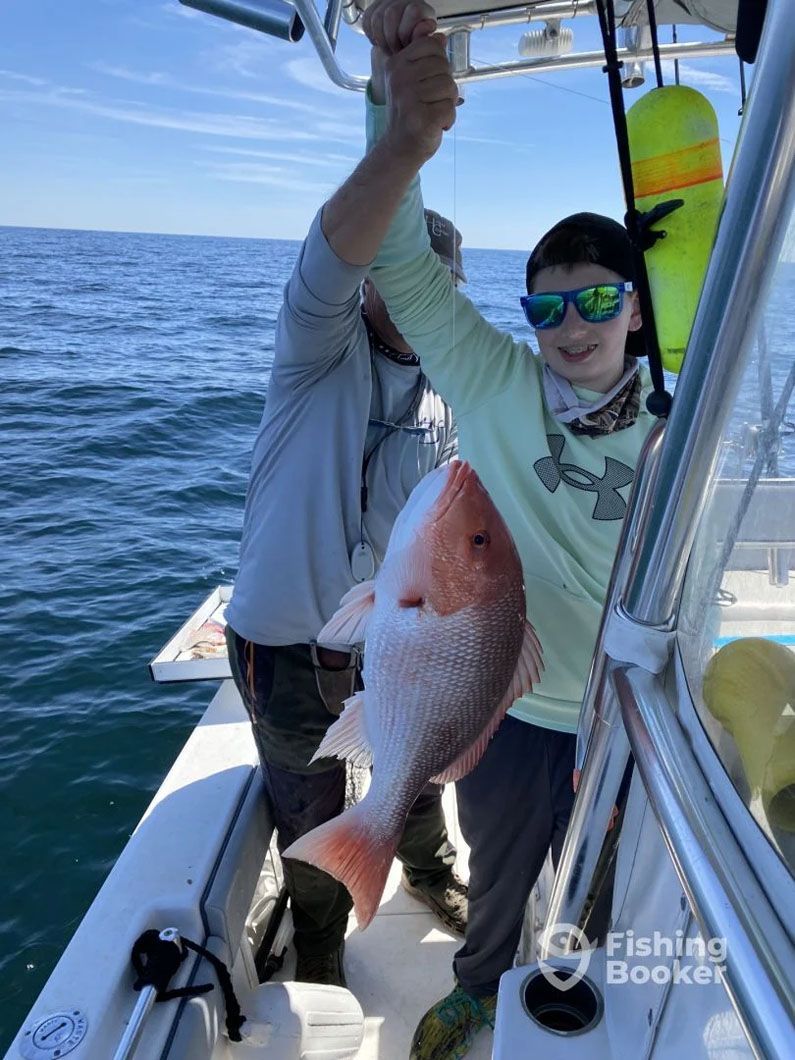 A man is holding a large red fish on a boat.