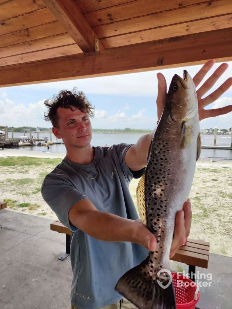 A man is holding a large fish under a fishing shelter