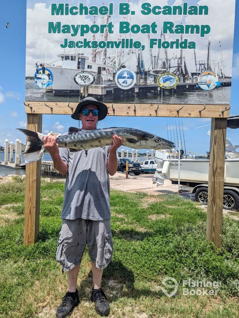 A man is holding a large fish in front of a sign.