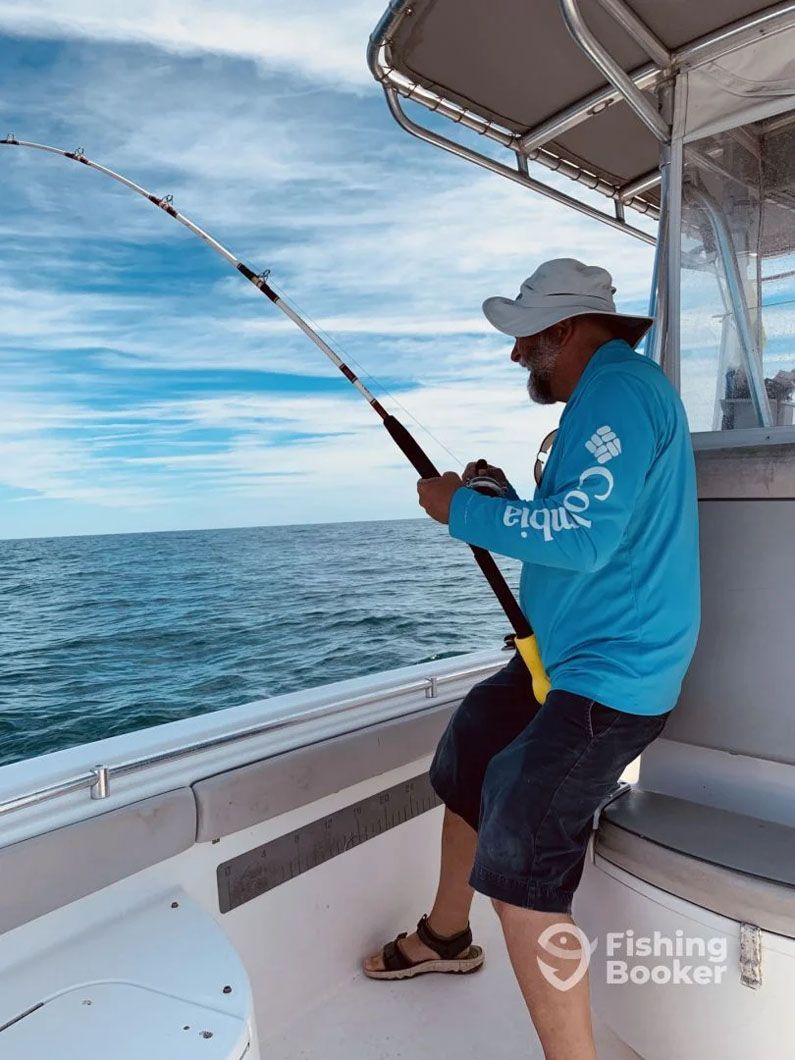 A man is fishing on a boat in the ocean.
