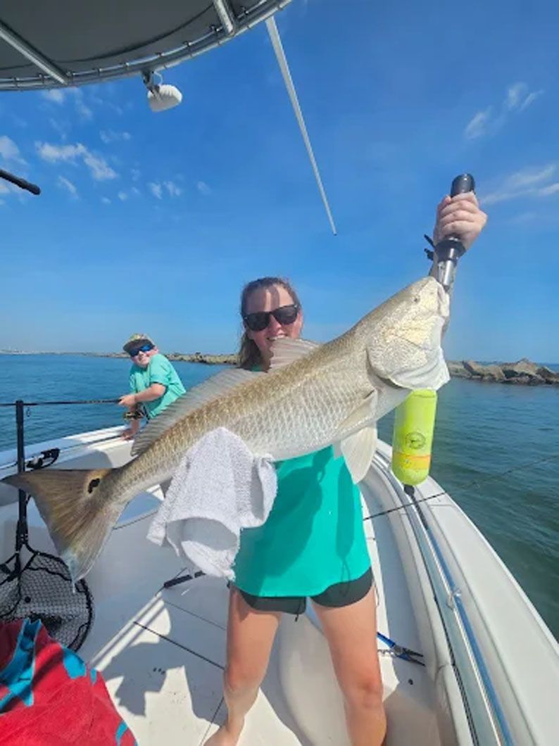 A woman is holding a large fish on a boat.