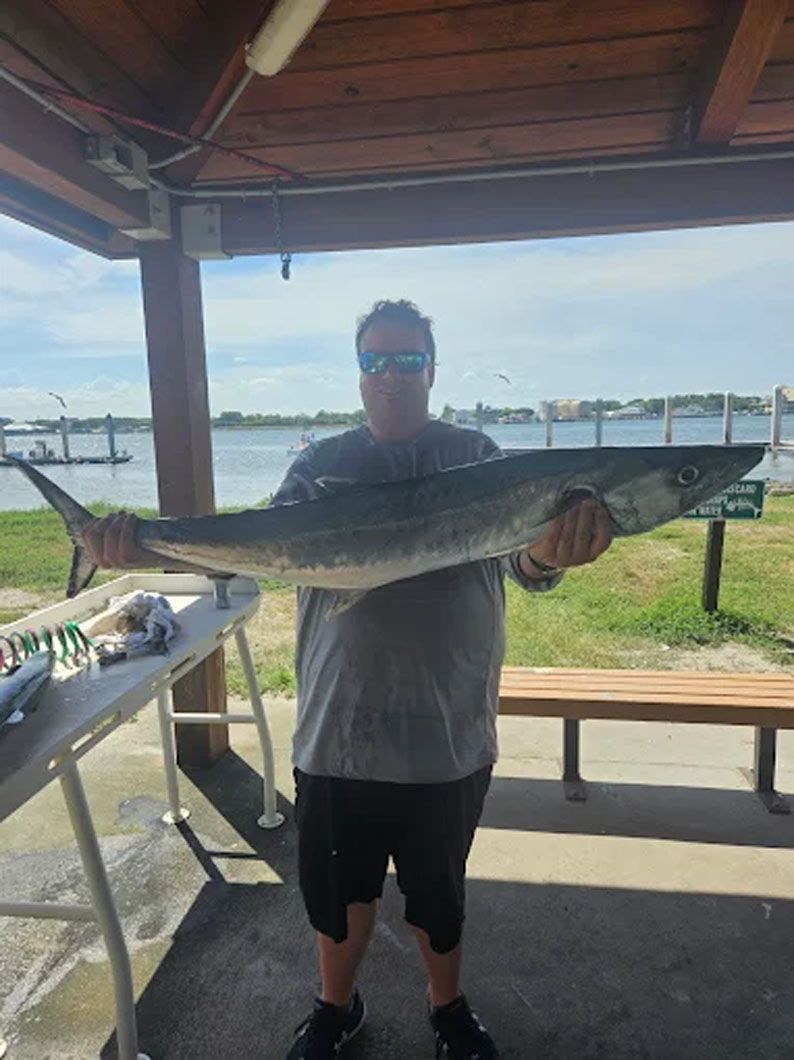 A man is holding a large fish in his hands.