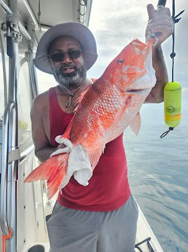 A man is holding a large red fish on a boat.