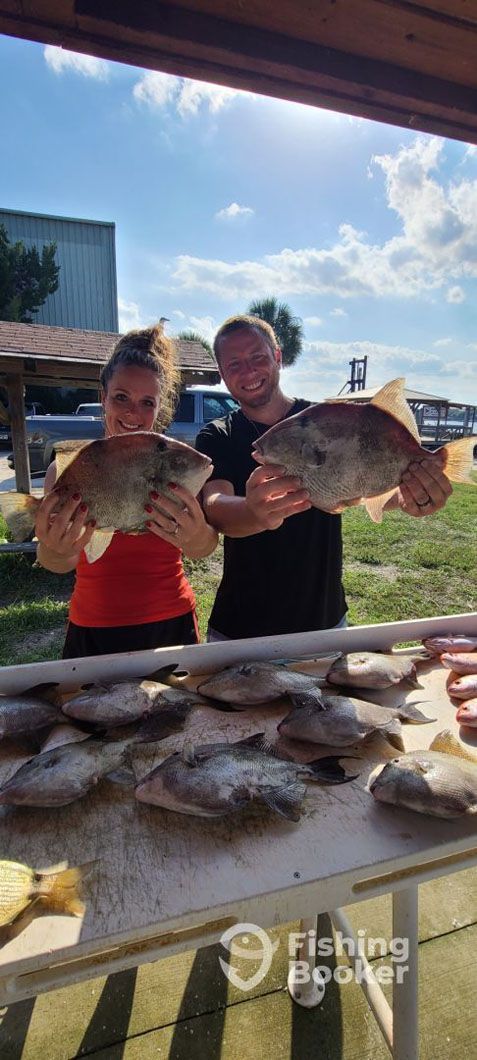 A man and a woman are holding a large fish in their hands.