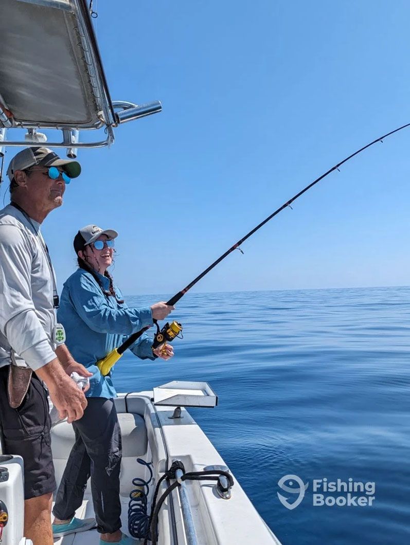 Two men are fishing on a boat in the ocean.