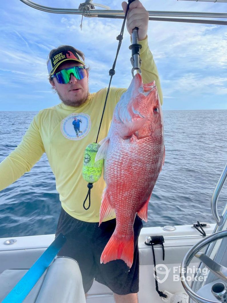 A man is holding a large red fish on a boat.