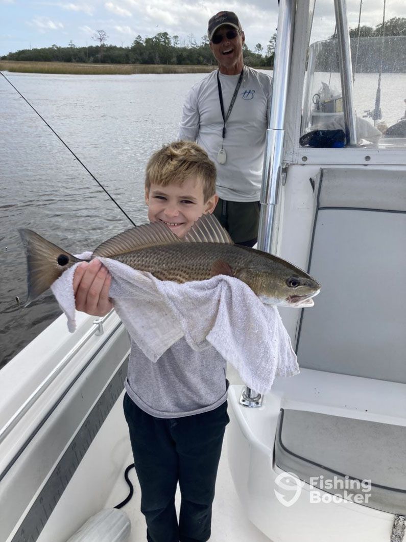 A young boy is holding a large fish on a boat.
