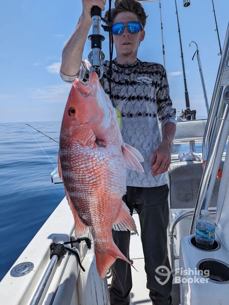 A man is holding a large red fish on a boat.