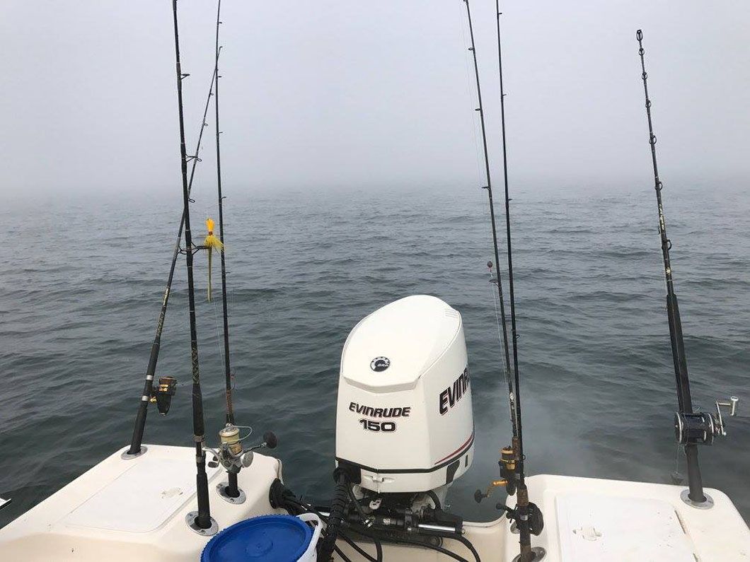 A boat with fishing rods and a motor in the water.