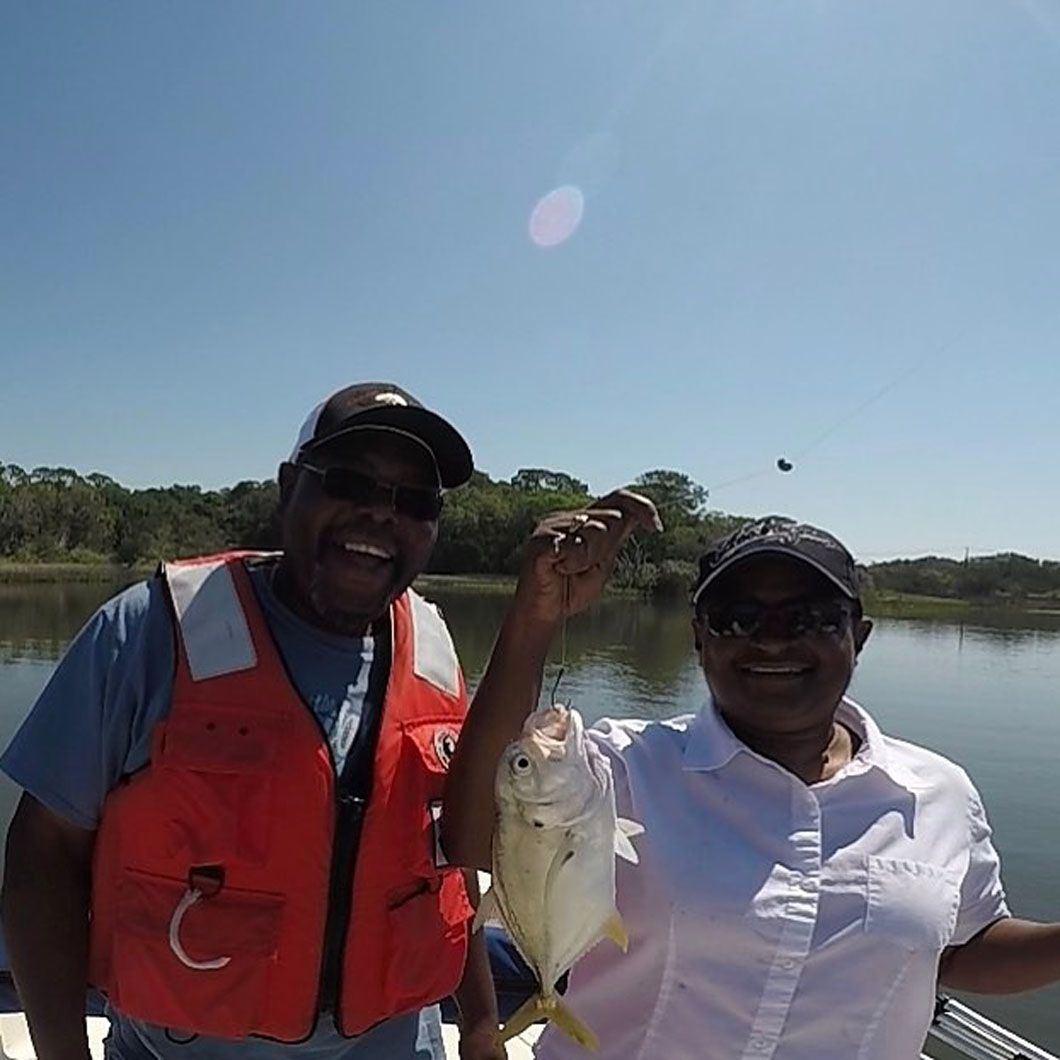A man and a woman are standing on a boat holding a fish.