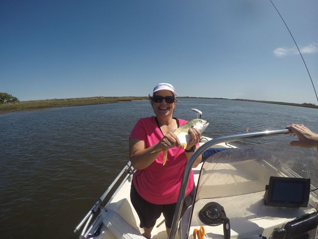 A woman is standing on a boat holding a fish.