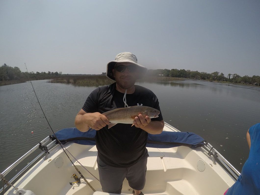 A man is standing on a boat holding a fish in his hands.