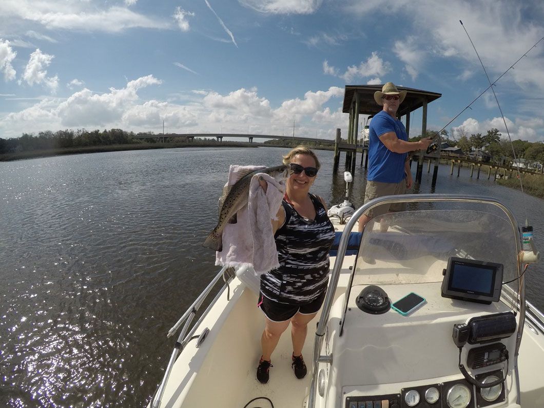 A woman is holding a fish while standing on a boat.