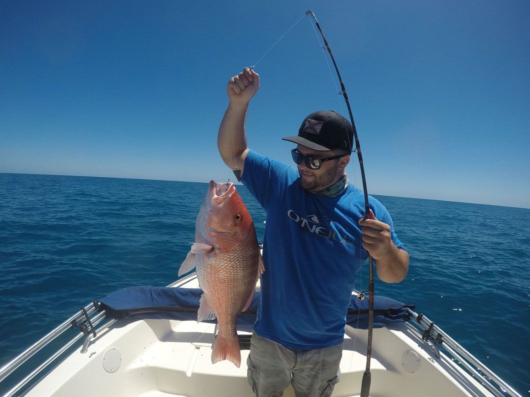 A man is holding a large fish on a boat in the ocean.