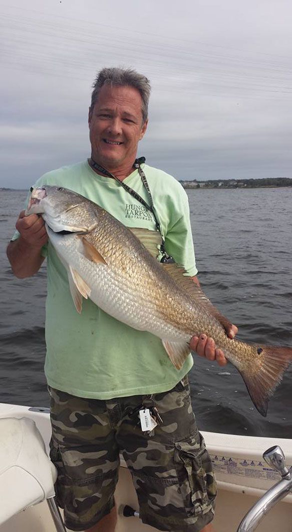 A man is standing on a boat holding a large fish.