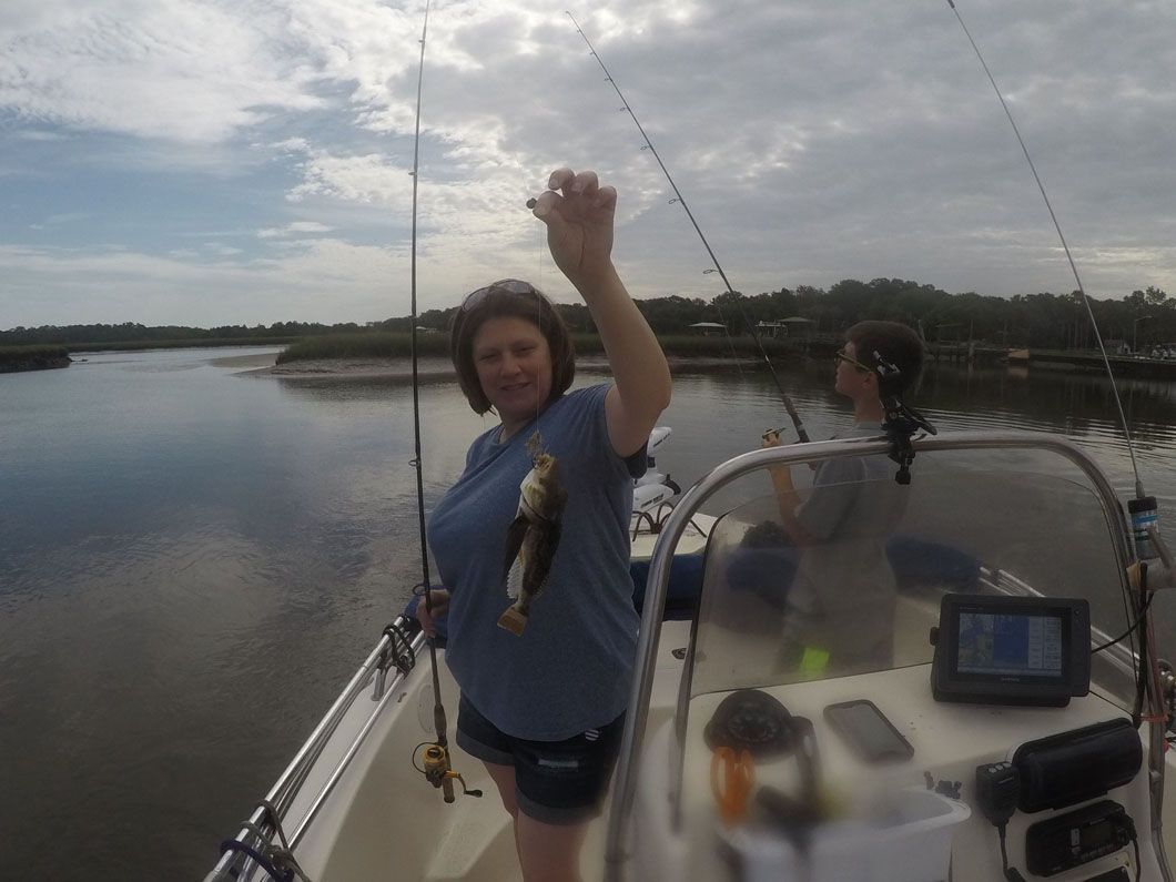 A woman is standing on a boat holding a fish in her hand.