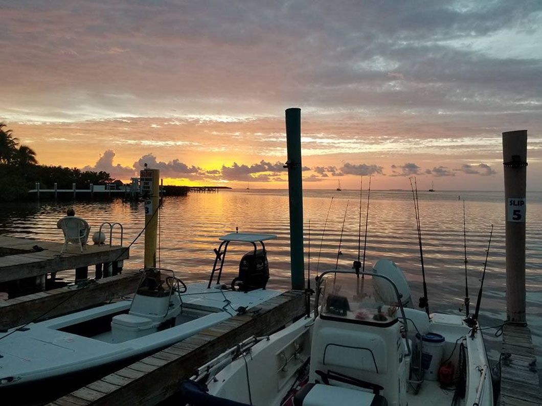 A sunset over a body of water with boats docked at a dock.