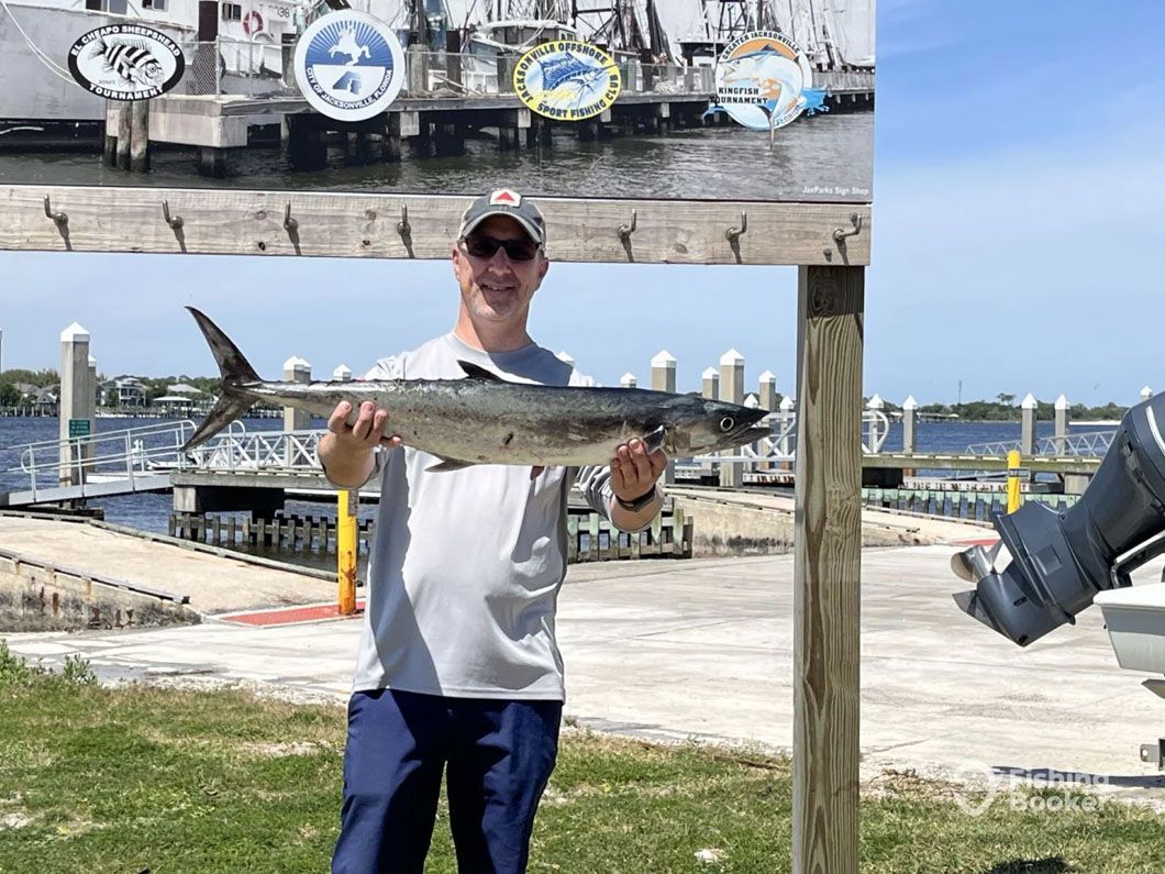 A man is holding a large fish in his hands in front of a boat.