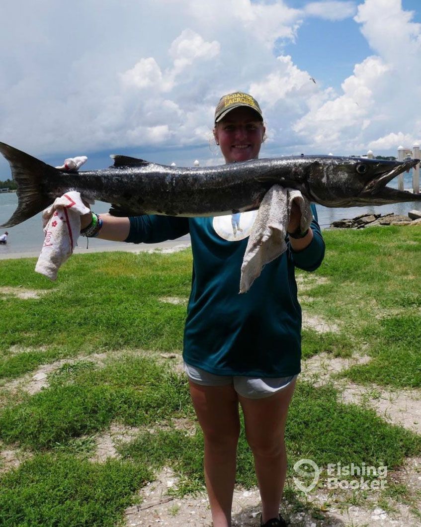 A woman is holding a large fish in her hands.