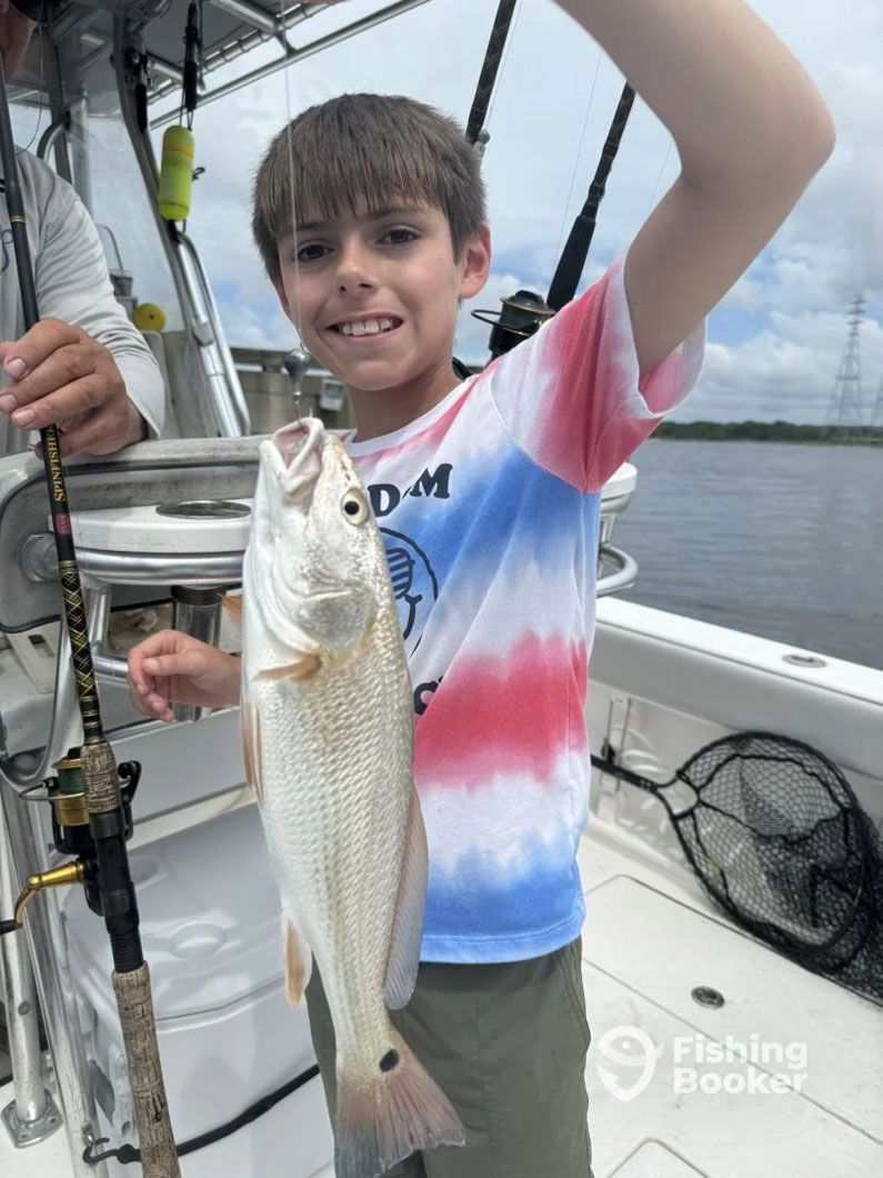 A young boy is holding a fish on a boat.