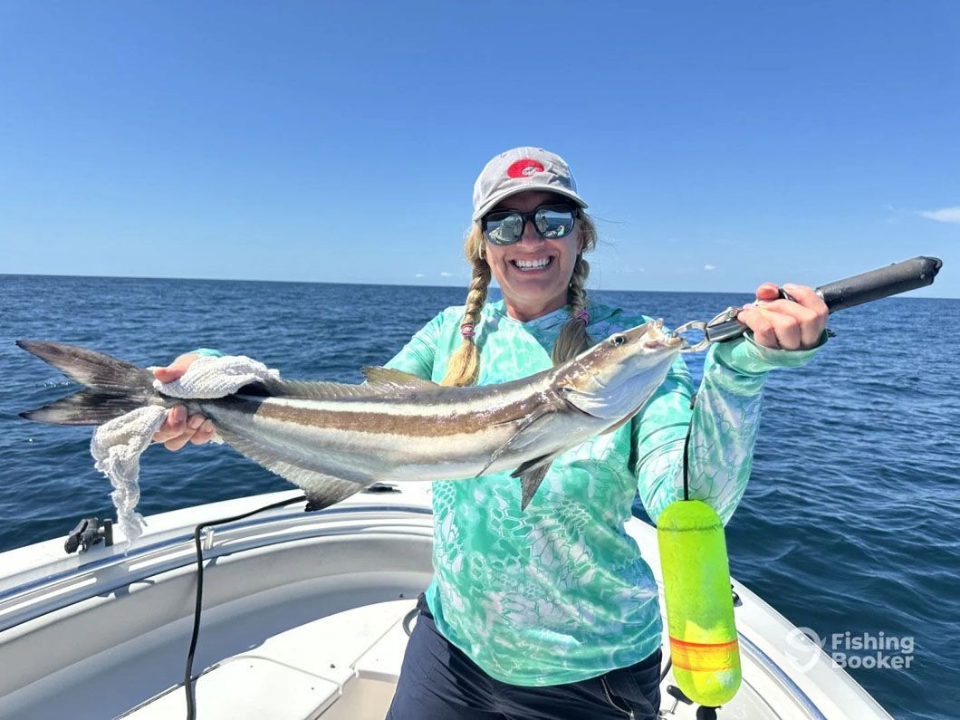 A woman is holding a large fish on a boat in the ocean.