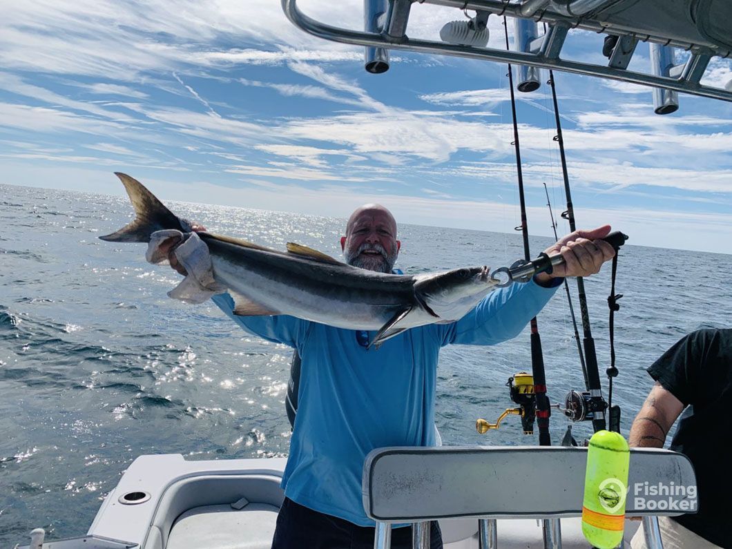 A man is holding a large fish on a boat.