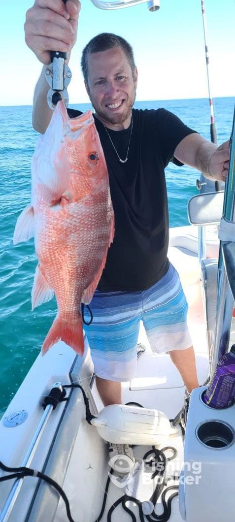 A man is holding a large red fish on a boat.