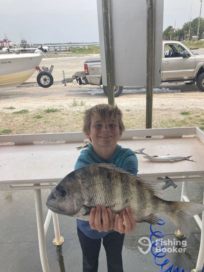 A young boy is holding a large fish in his hands.