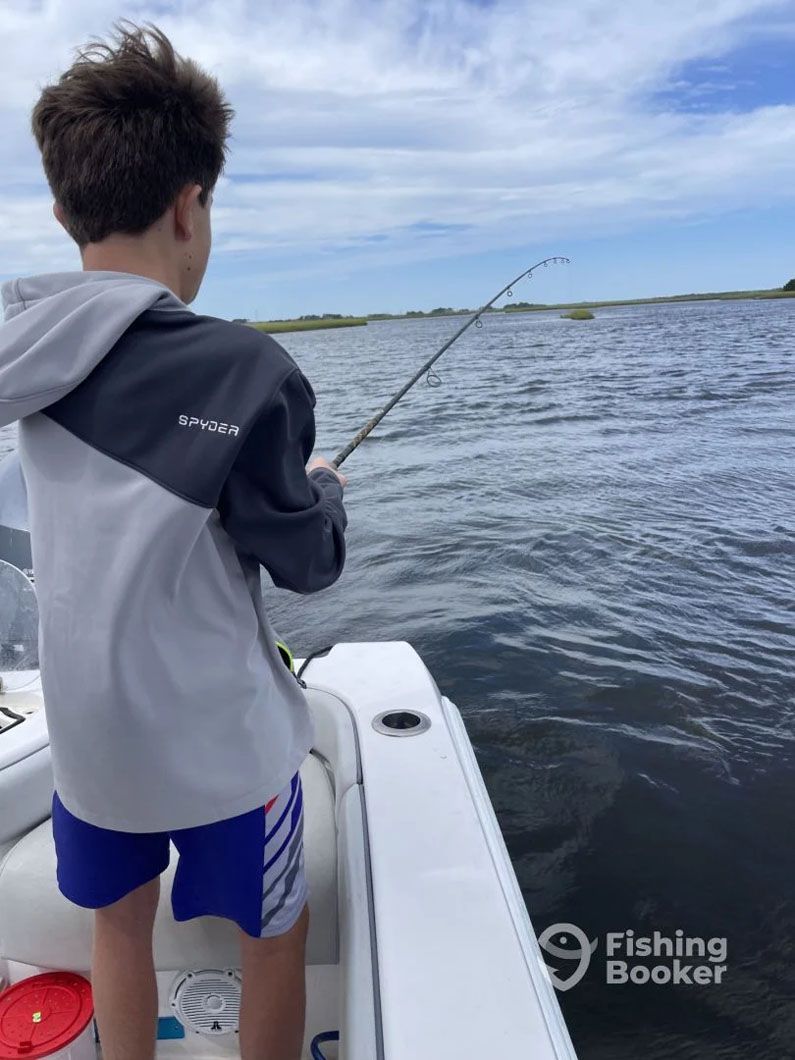 A young boy is fishing on a boat in the water.