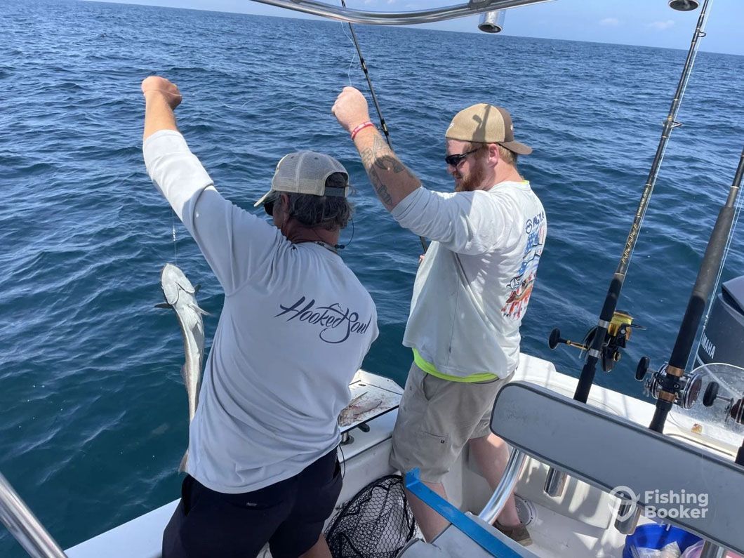 Two men are fishing on a boat in the ocean.