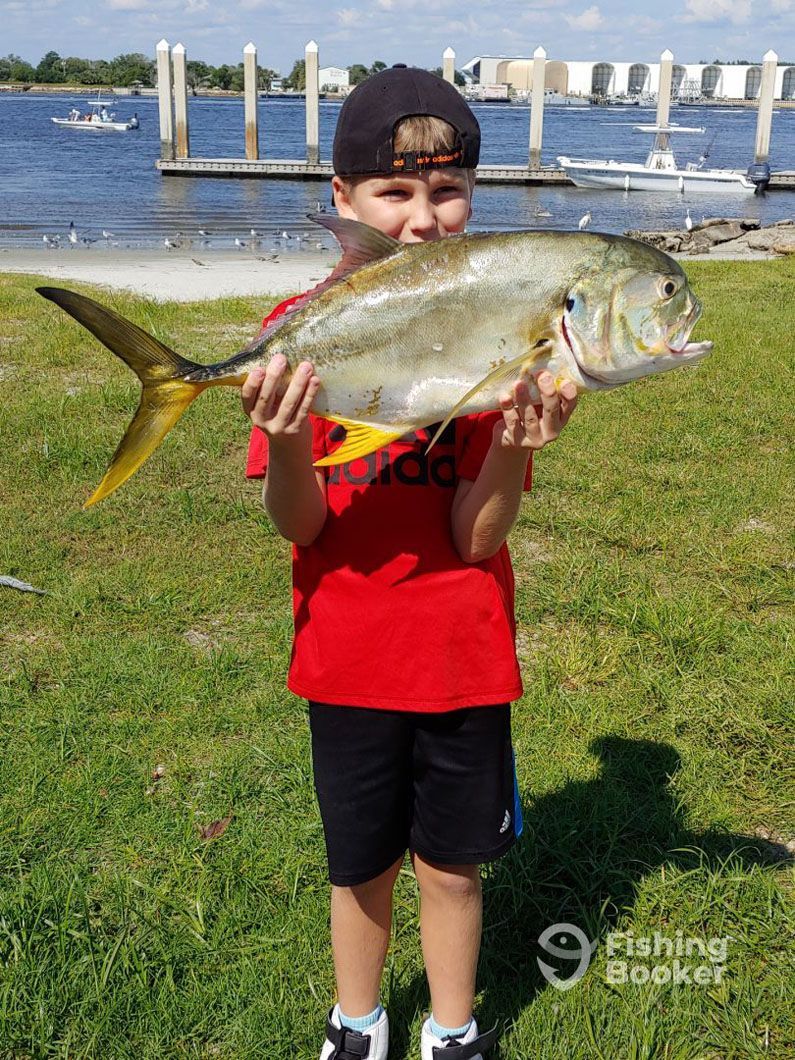 A young boy is holding a large fish in his hands.