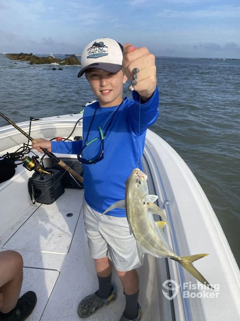 A young boy is holding a fish on a boat.