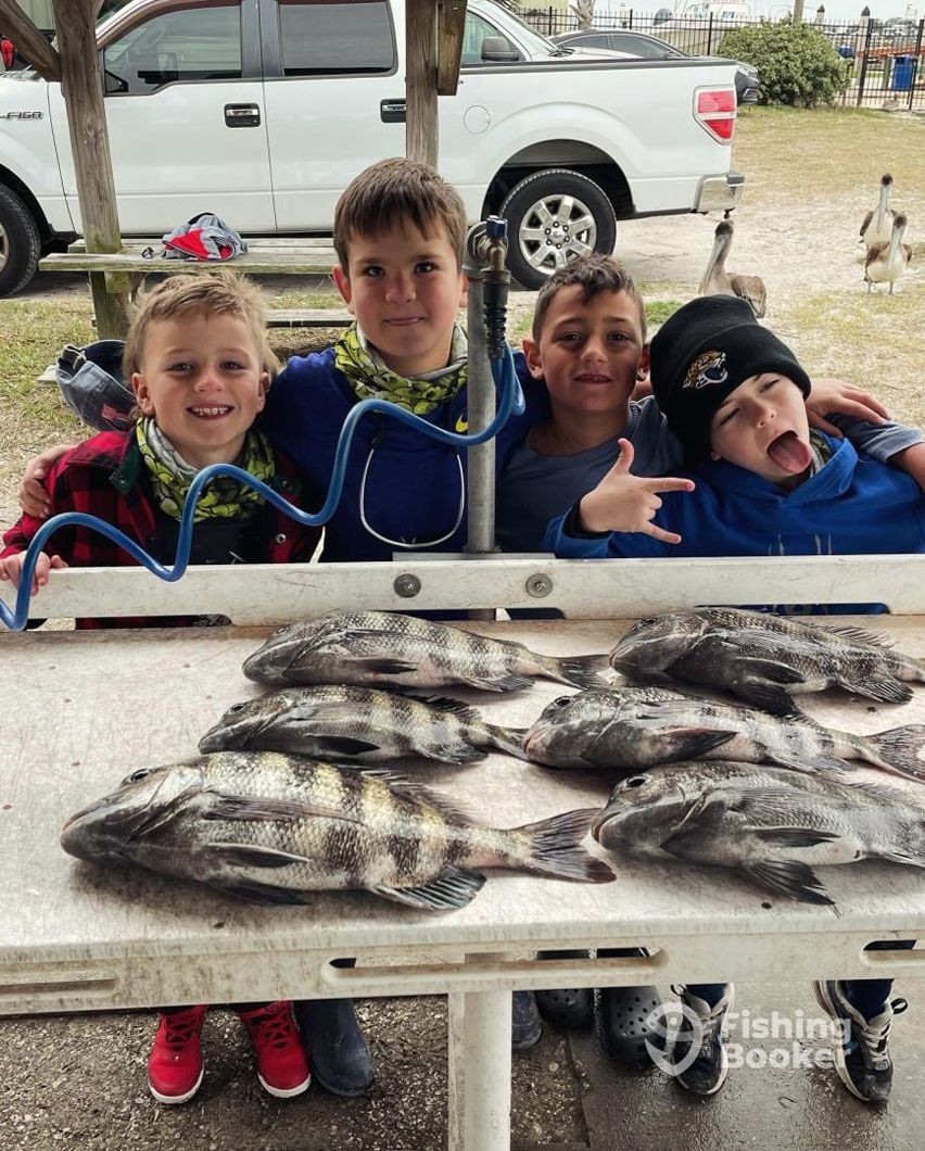 A group of young boys standing next to a table with fish on it.