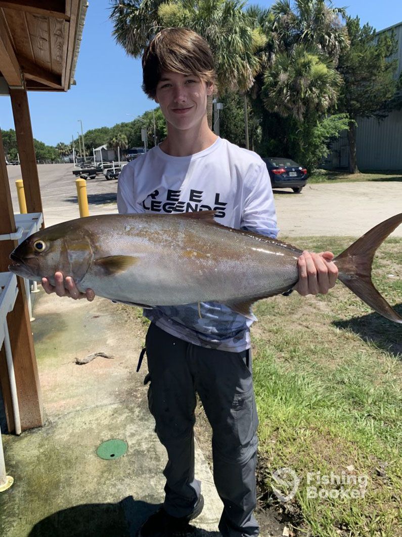 A young man is holding a large fish in his hands.