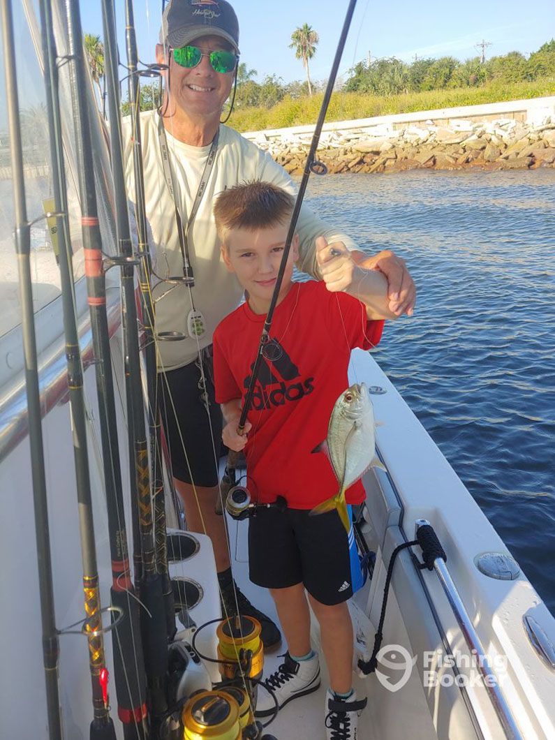 A man and a boy are fishing on a boat.