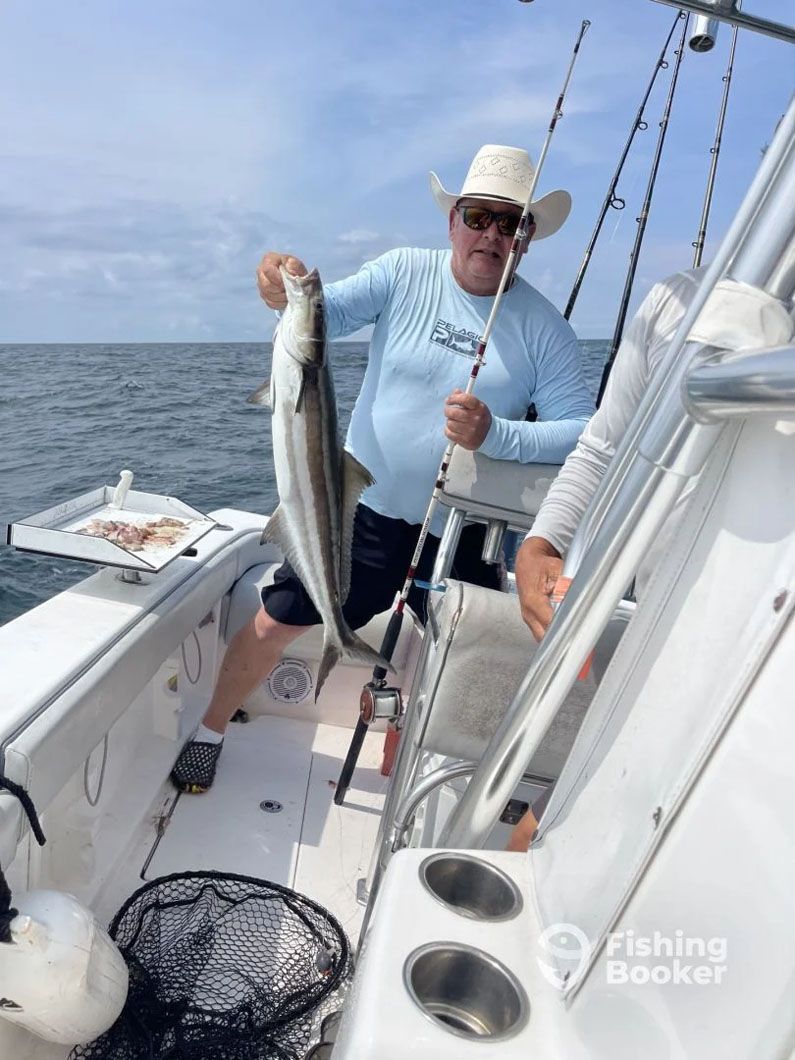 A man is holding a large fish on a boat.