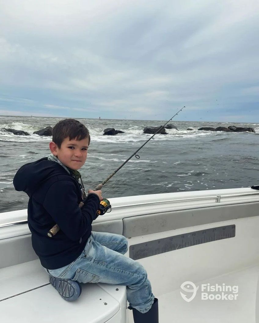 A young boy is sitting on a boat holding a fishing rod.